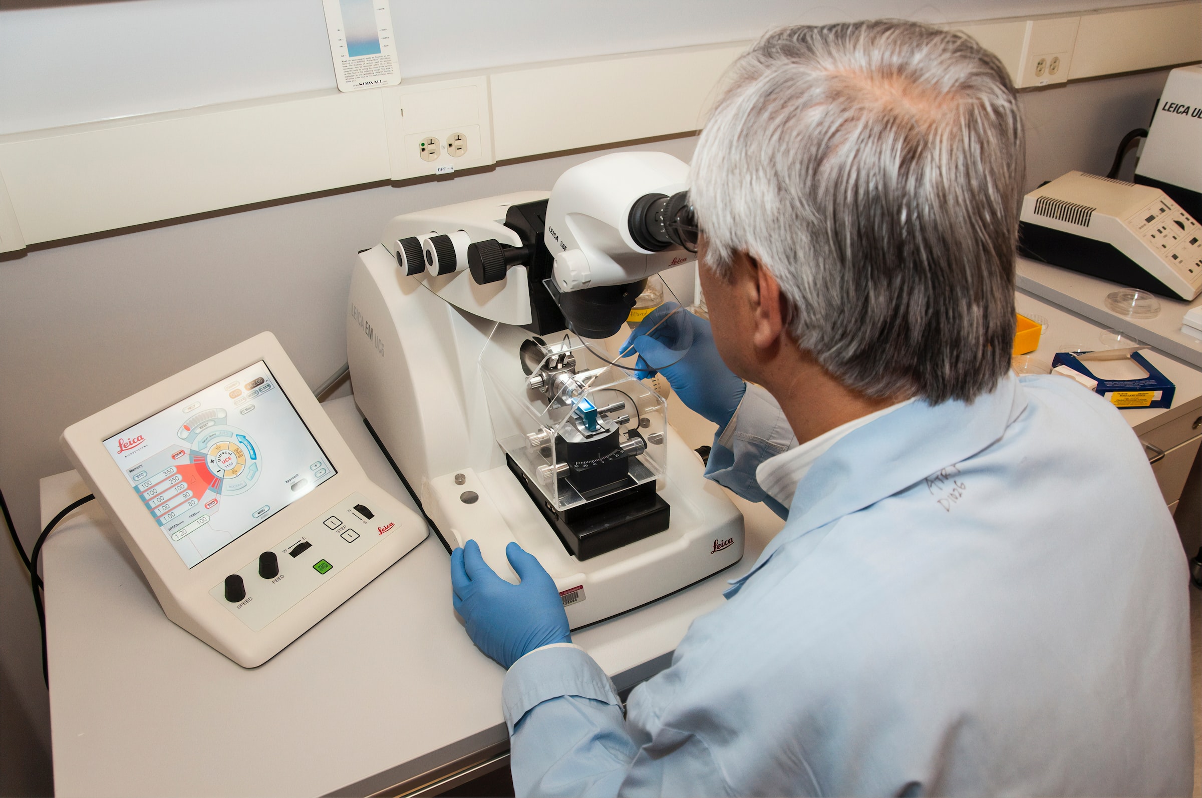 Male scientist looking into microscope at assay