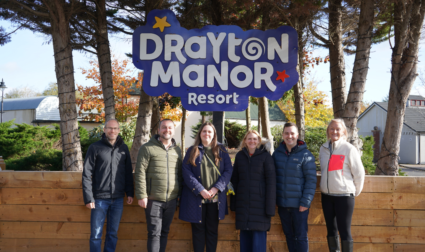 A group photo of people standing in front of the Drayton Manor logo.