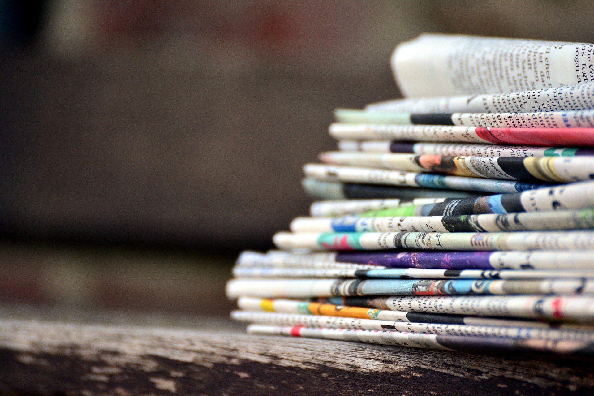 A stack of newspapers on a wooden table.