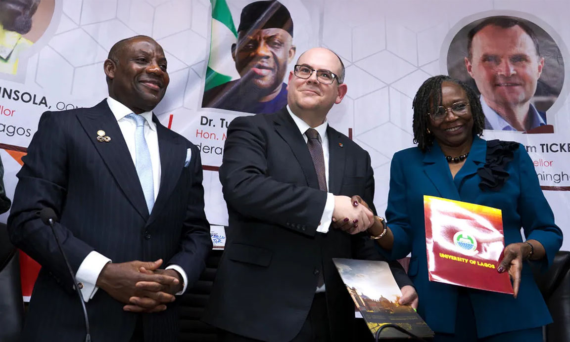 Professor Nick Vaughan-Williams shaking hands with Professor Folasade Ogunsola as they exchange documents