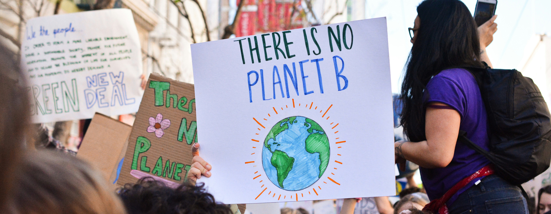 Environmental protesters holding up placards, with a homemade sign that reads 'There is no Planet B'