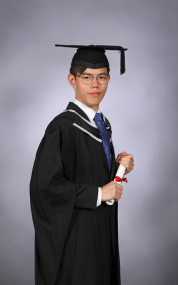 Profile picture, man stood in graduate gown looking at the camera