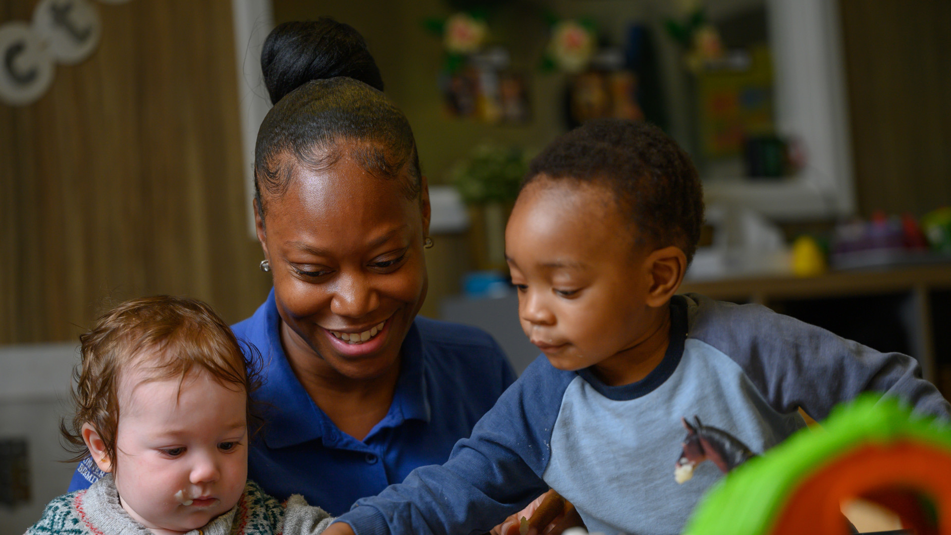 A staff member smiling with two children