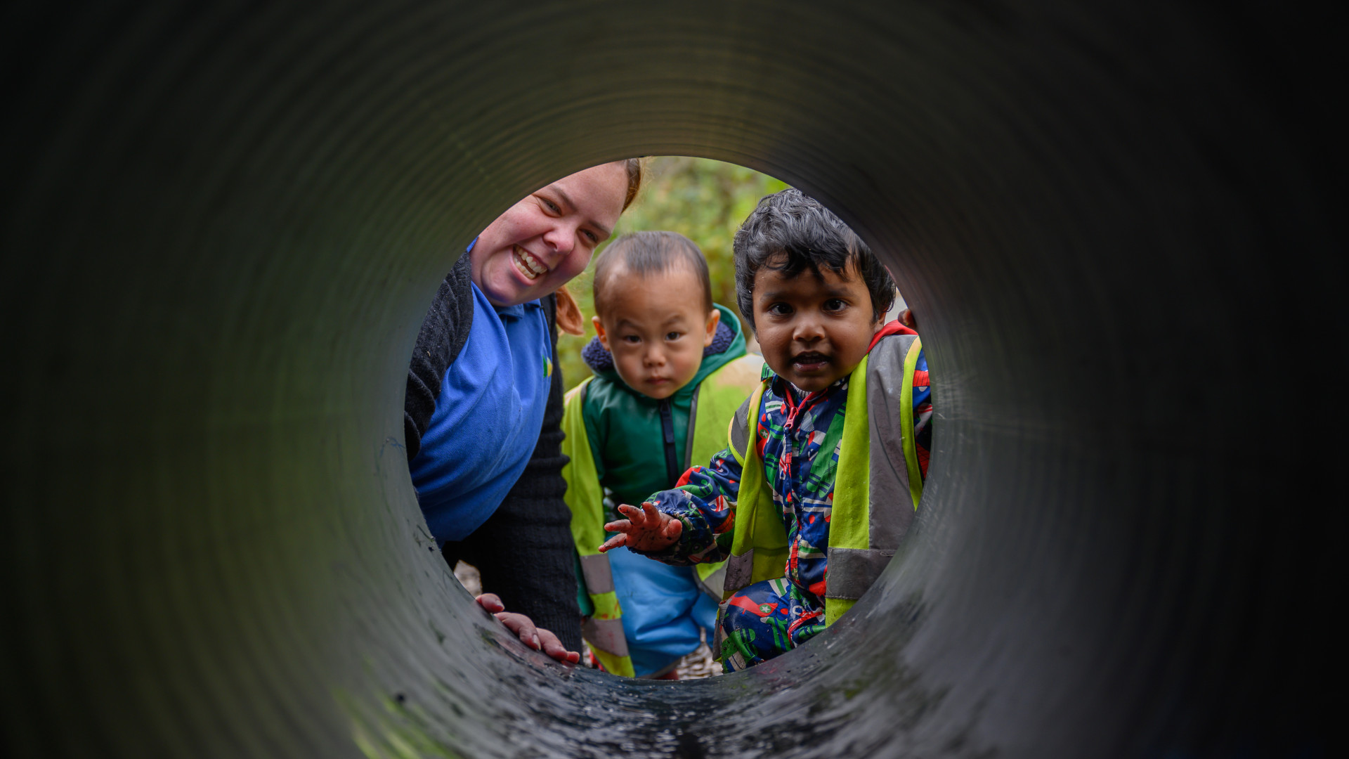 A staff member looking through a tunnel with two children