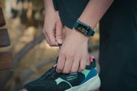 Close-up of young woman's hand tying her trainers' laces and showing a fitness tracker on her arm