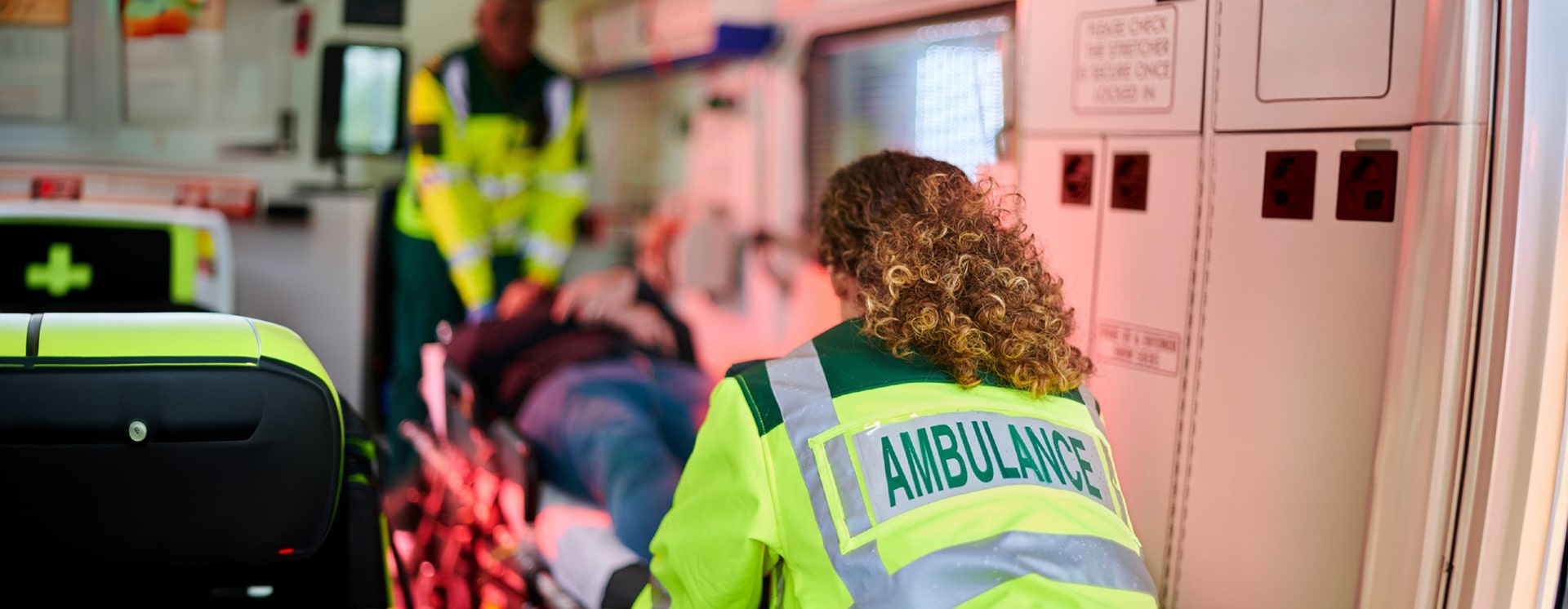 Paramedics inside an ambulance securing a patient on a gurney