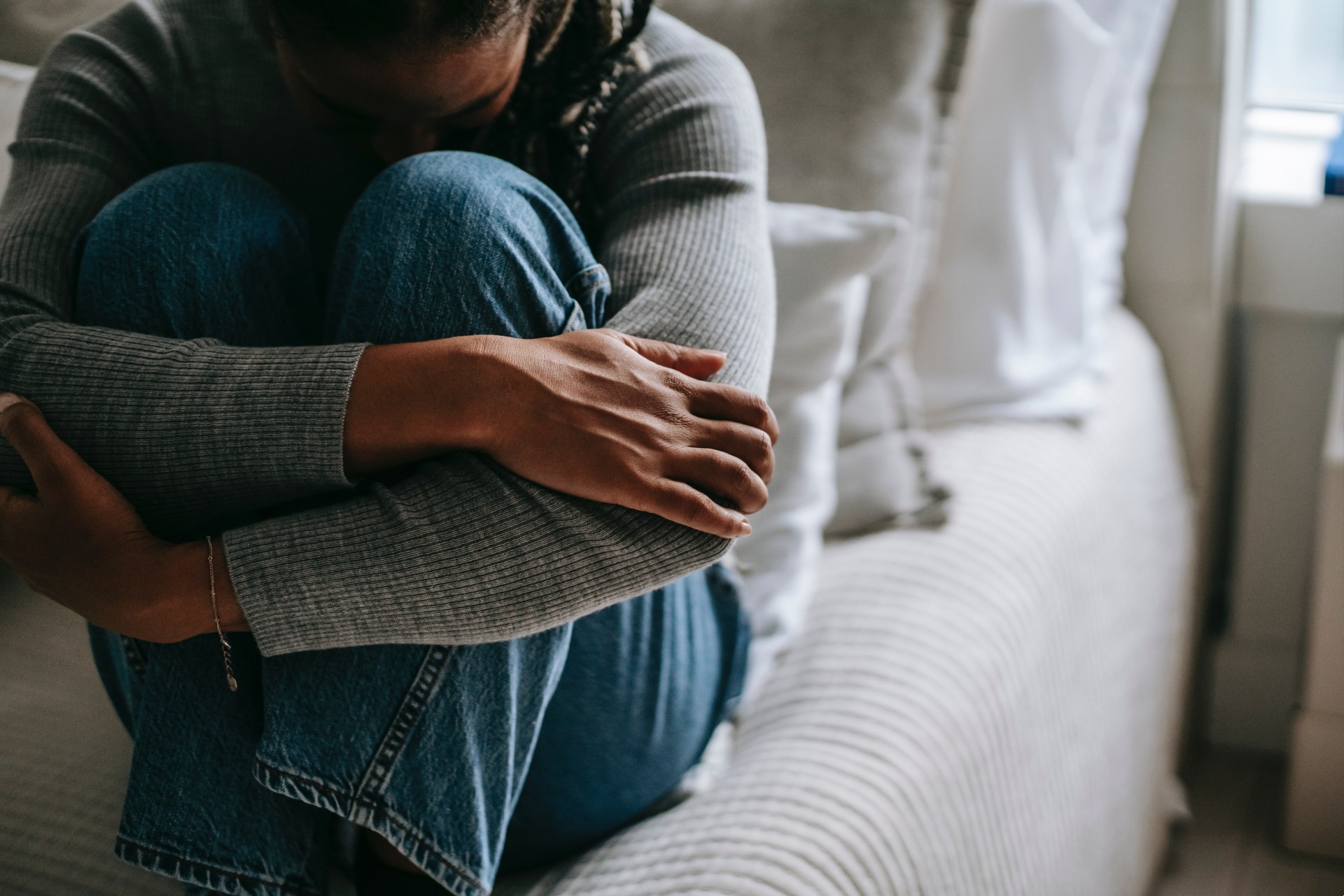 Girl sitting hunched on a bed