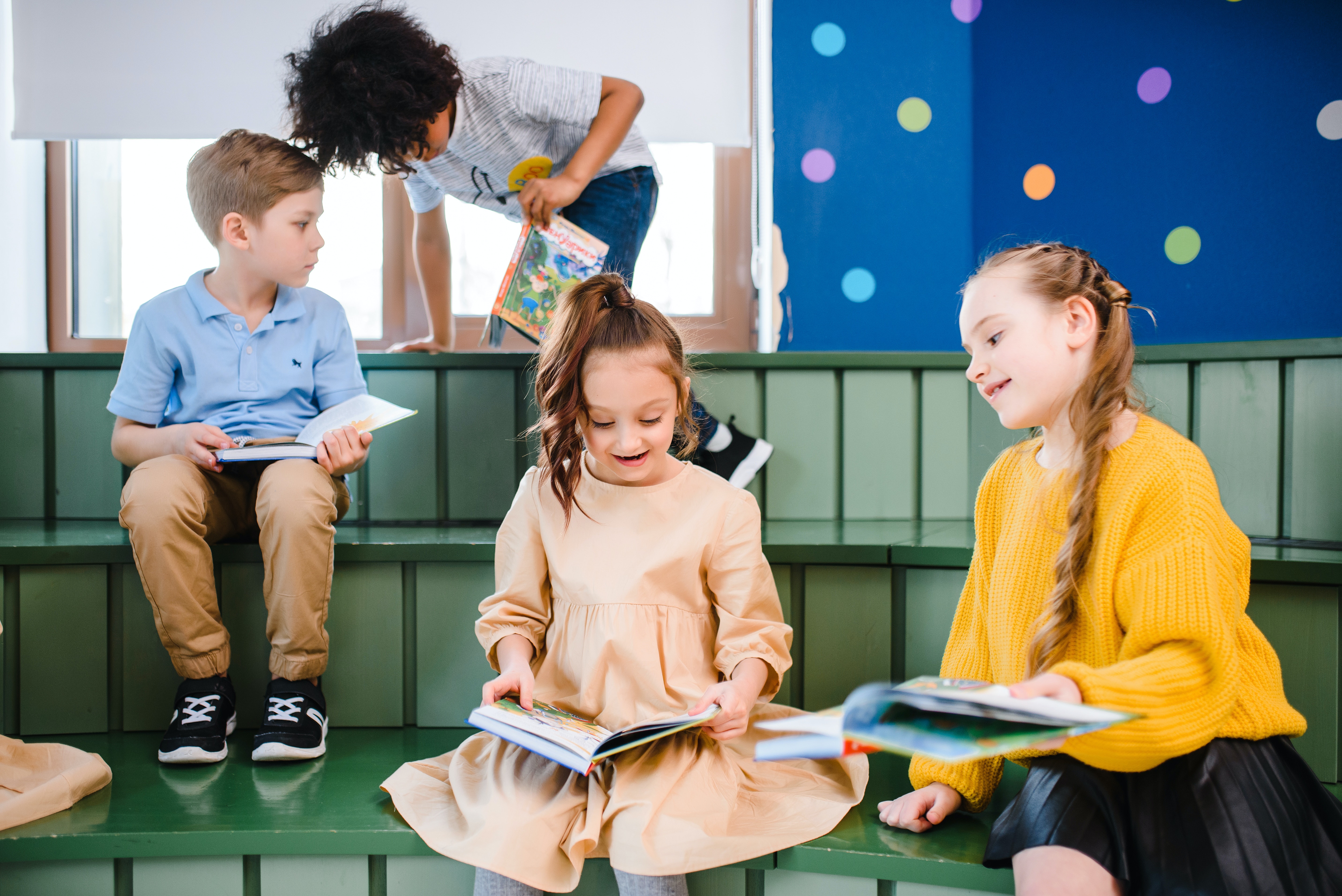 A group of four children reading children's books.