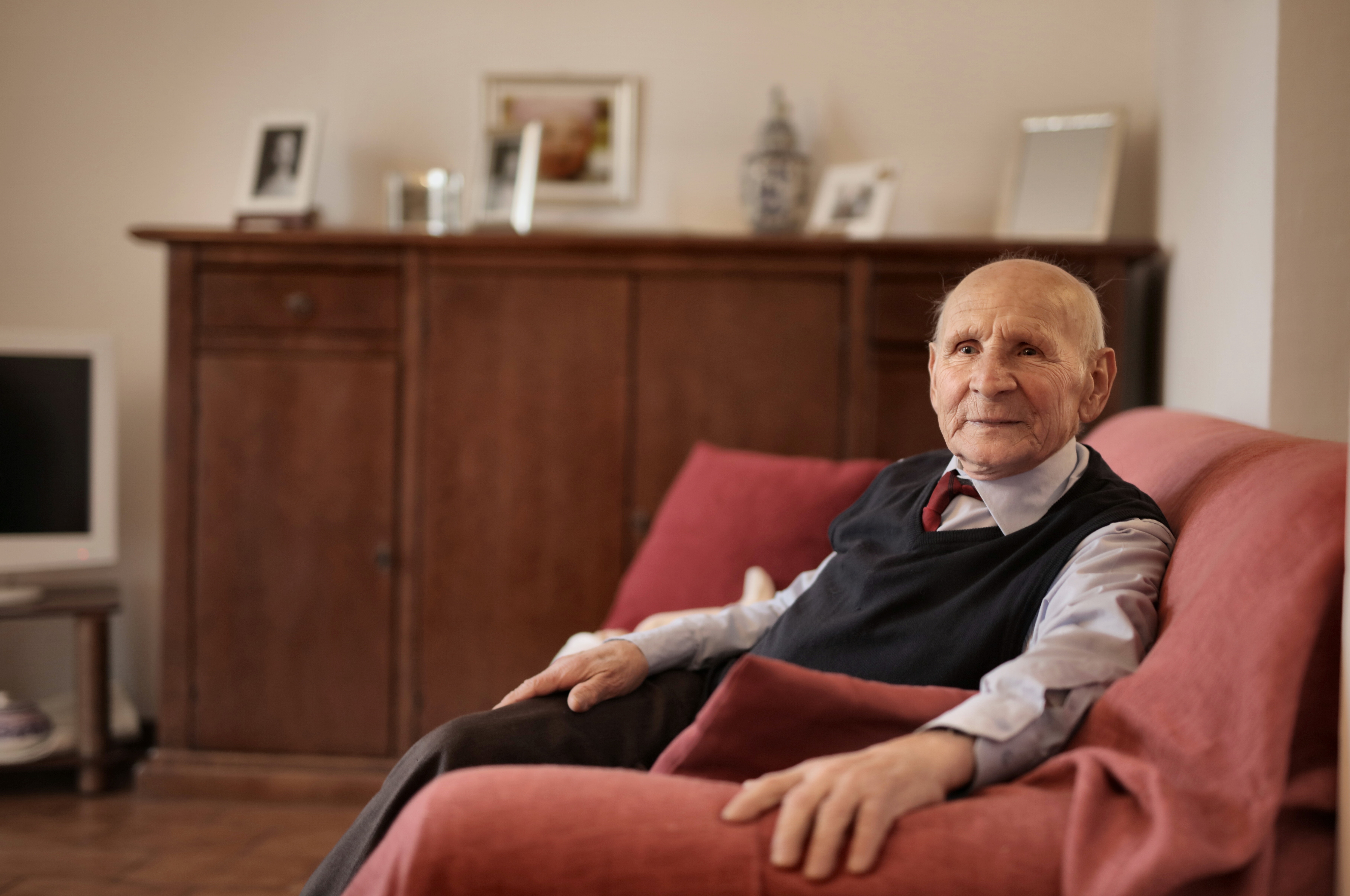 Elderly man sitting on a sofa in his home.