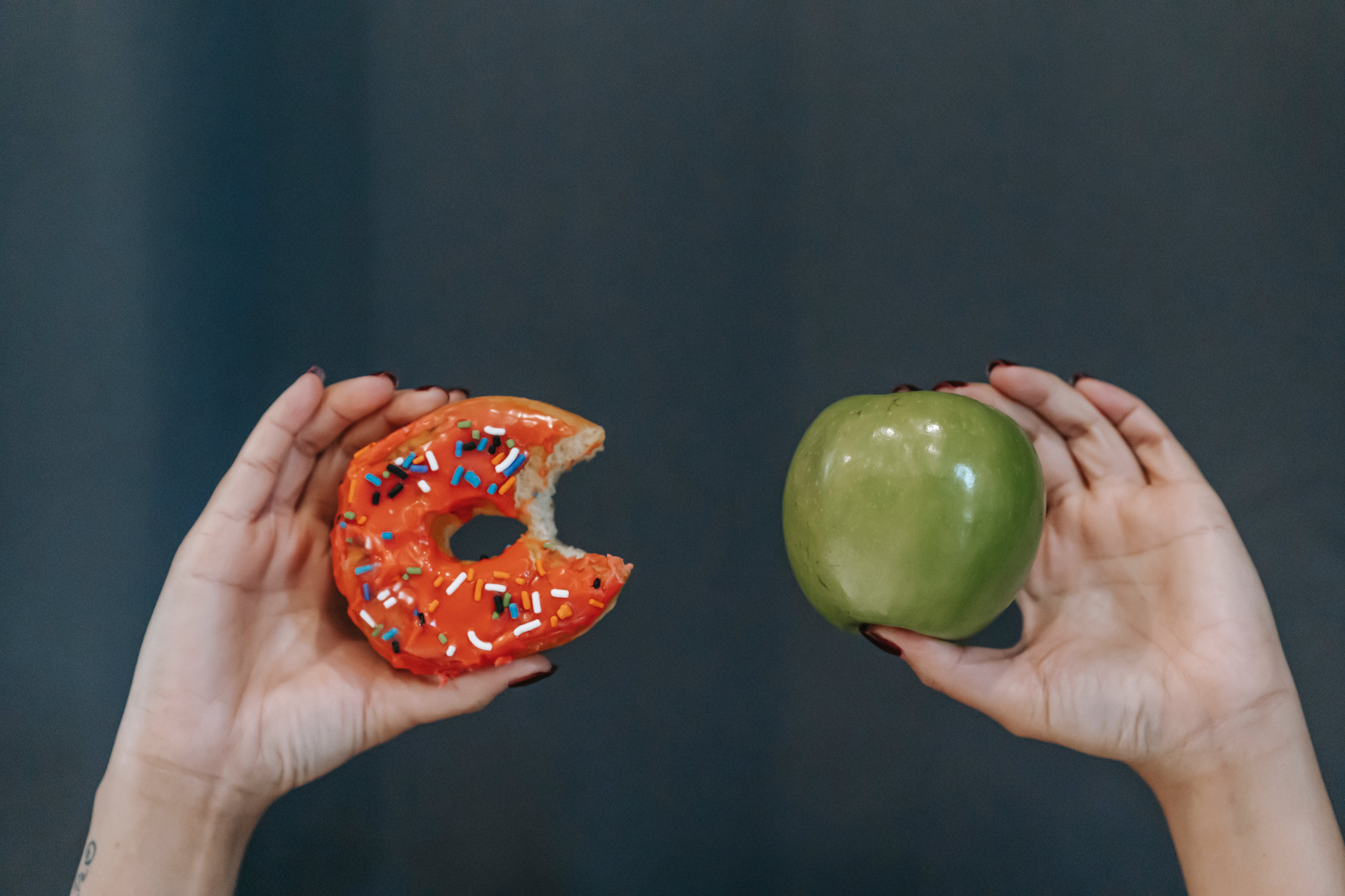 Hands holding a doughnut and an apple