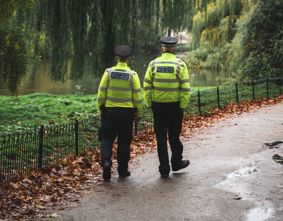 Two police officers walking in a park.