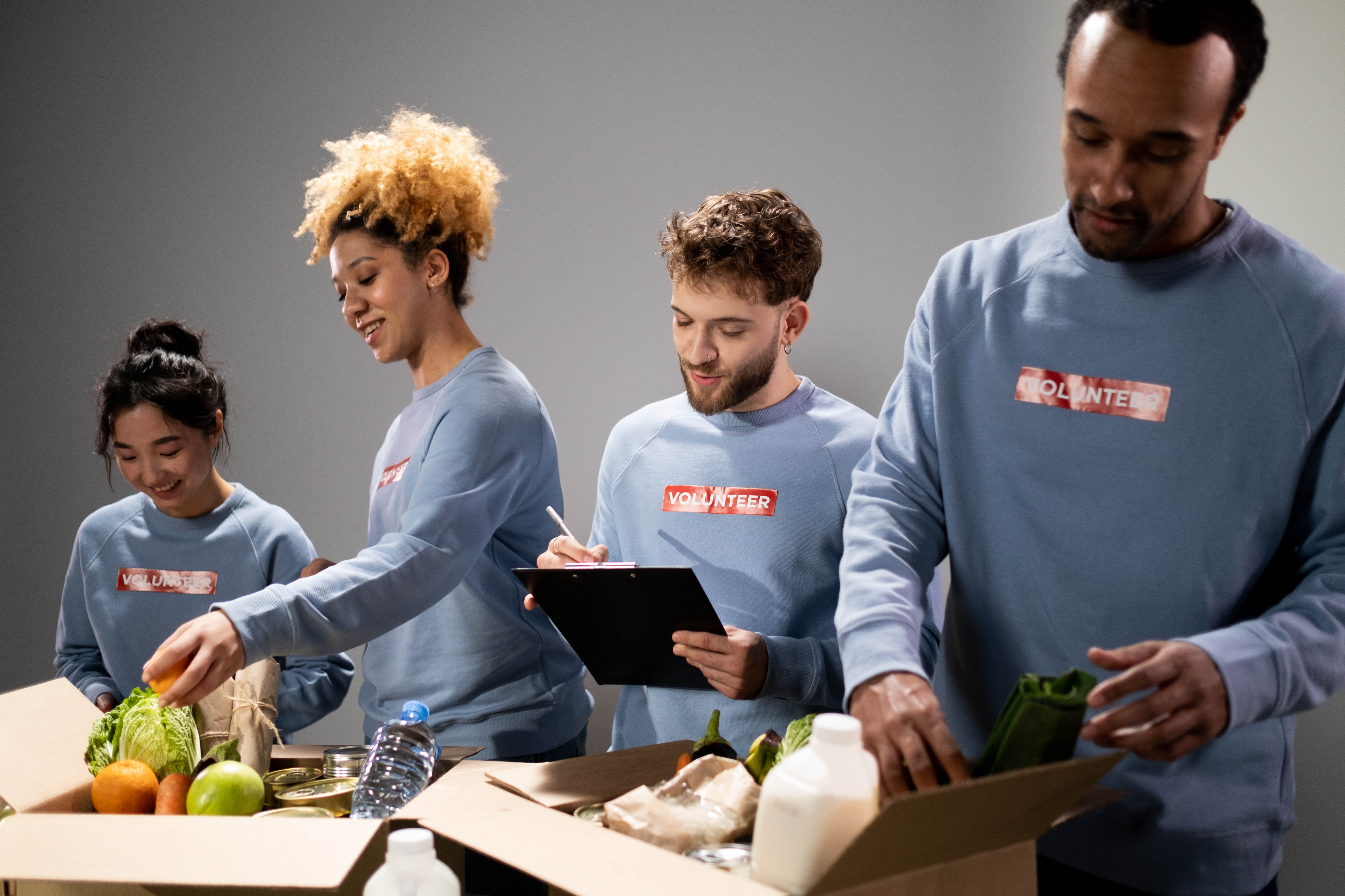 A group of young and diverse volunteers providing boxes off food.