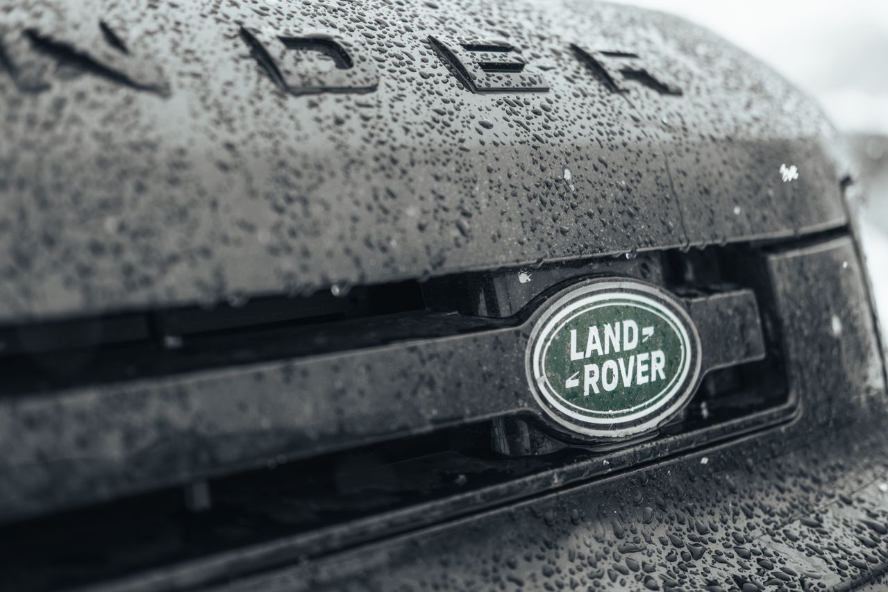 The front of a Land Rover Discovery with the Land Rover badge visible, in the rain.