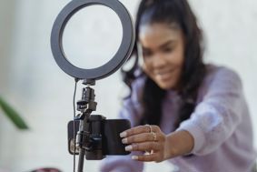 Young woman setting up a phone and ring light for recording.