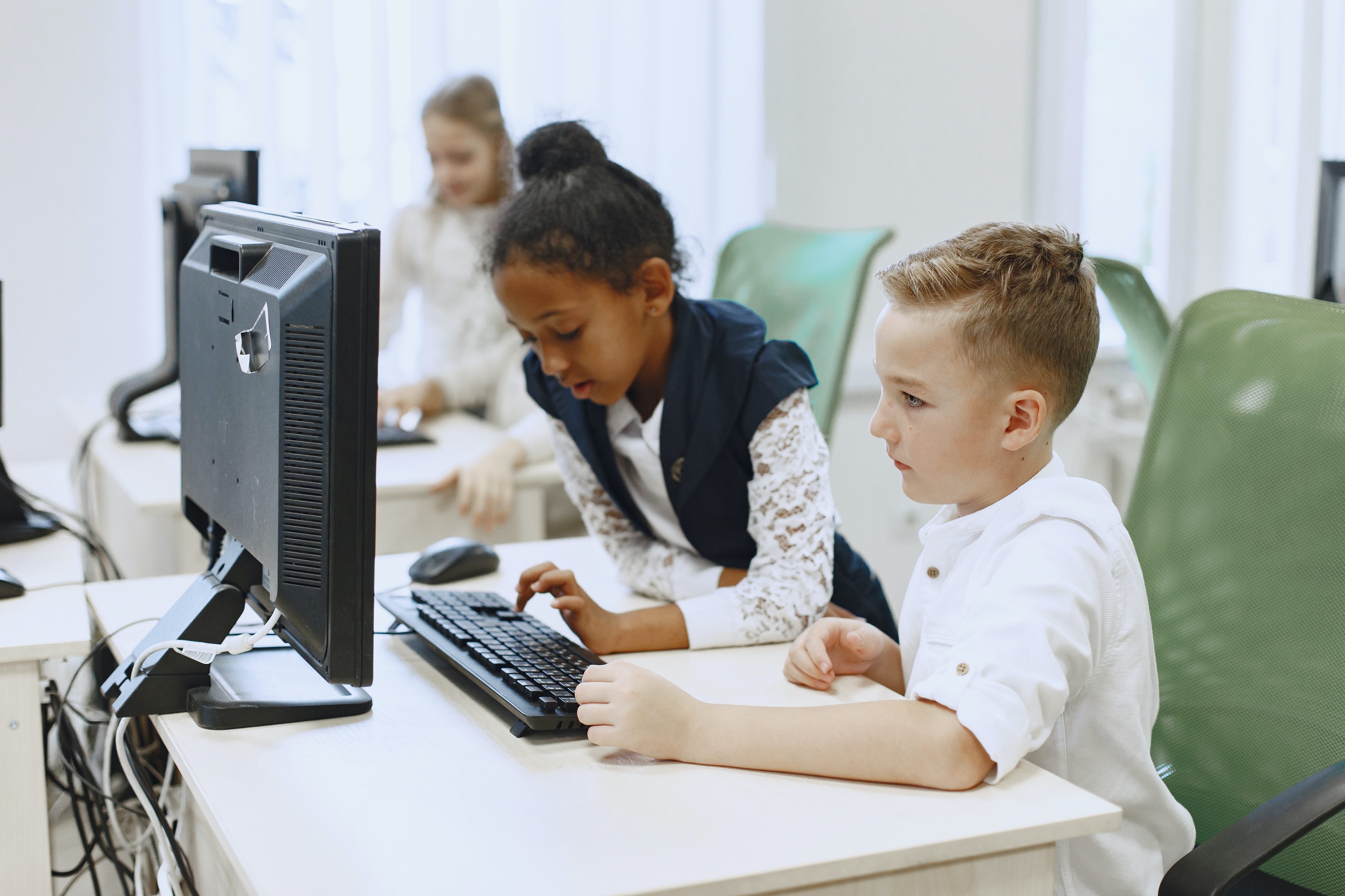 Two children, a boy and a girl working on a computer together.