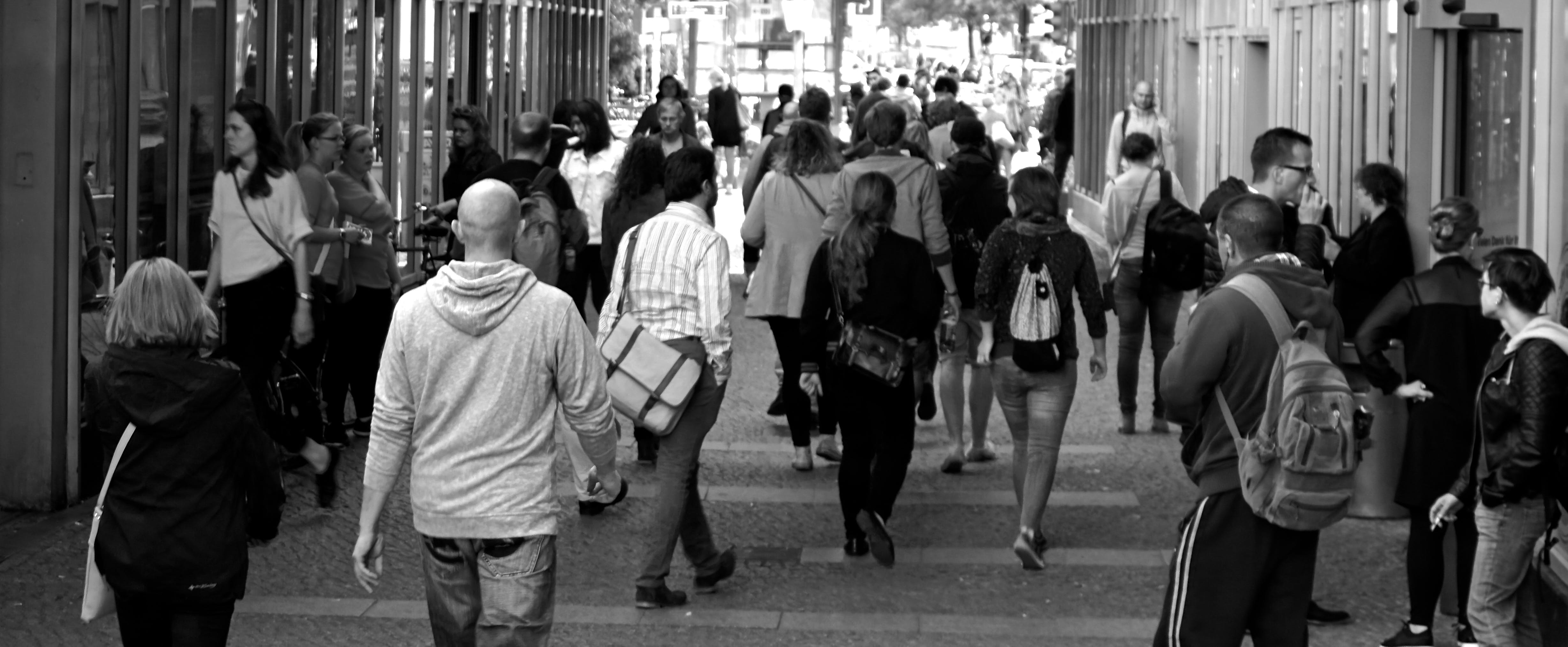 Black and white photo of people walking down a busy street in a city.