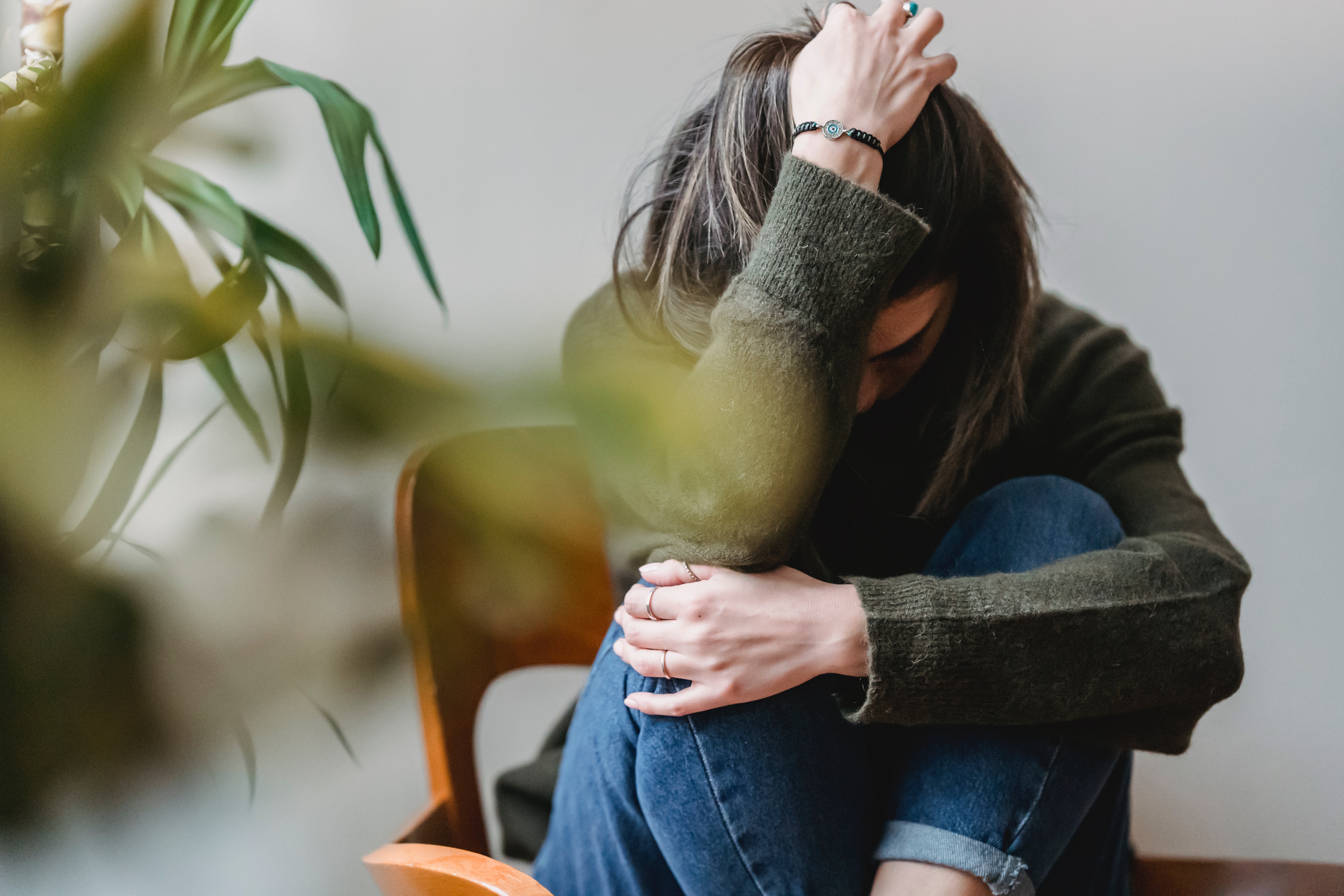 Sad woman sitting on a chair with her head down.