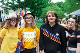Four young people with pride flags and badges. 