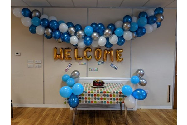 A table with a cake with ballons above it and around it