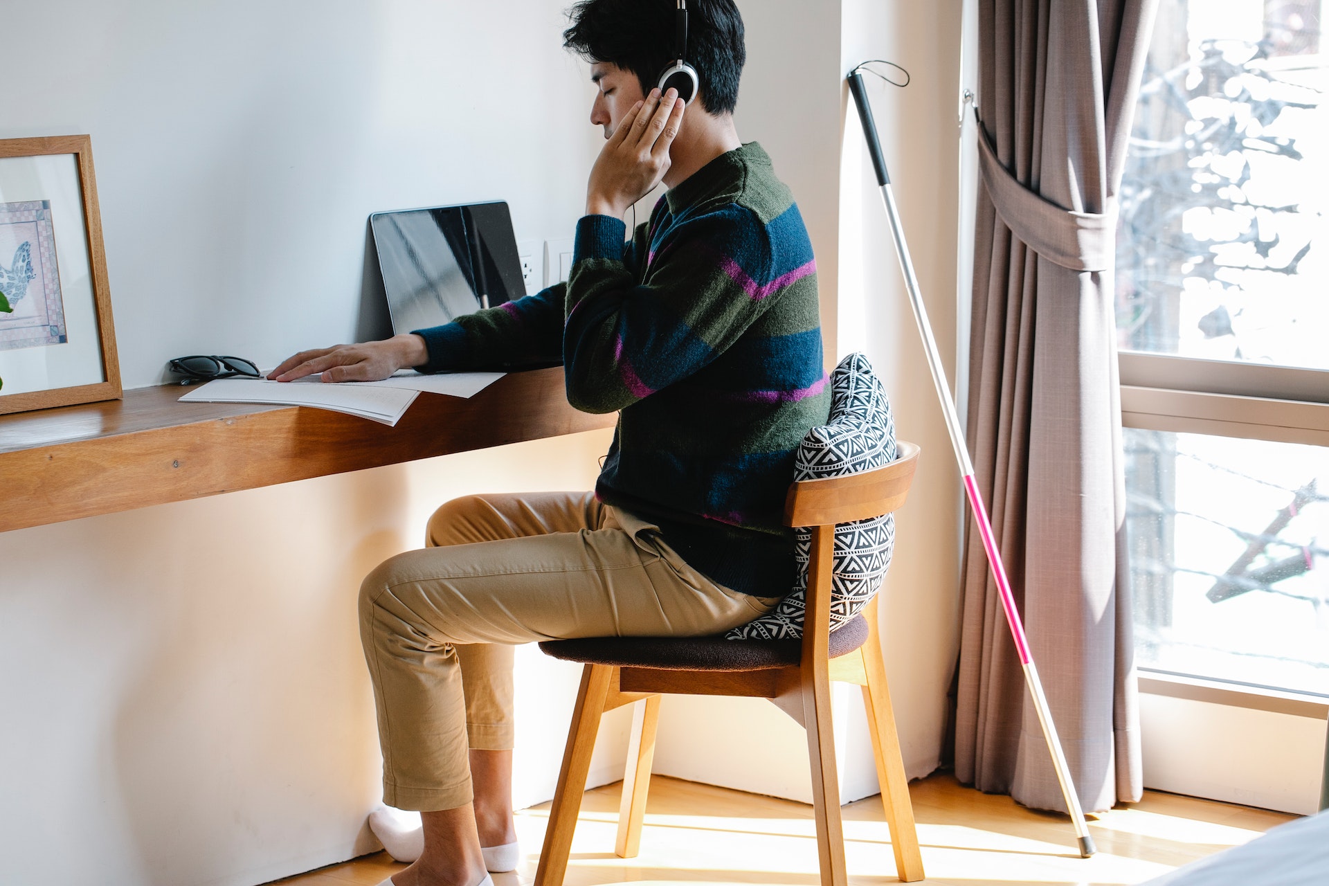 Photo of Man Using Headphones While Learning Braille