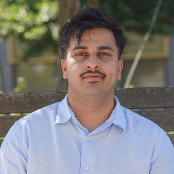 Pravin smiling into the camera with a backdrop of the university library