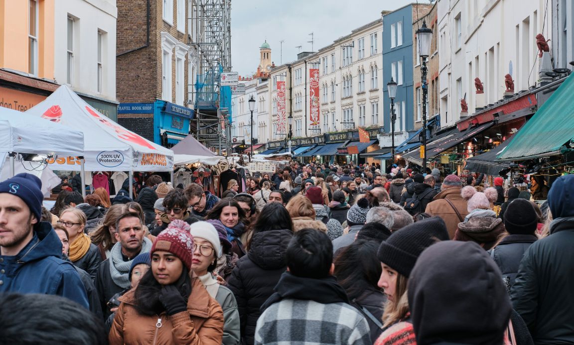A bustling street with a large crowd of people wearing winter clothes. 