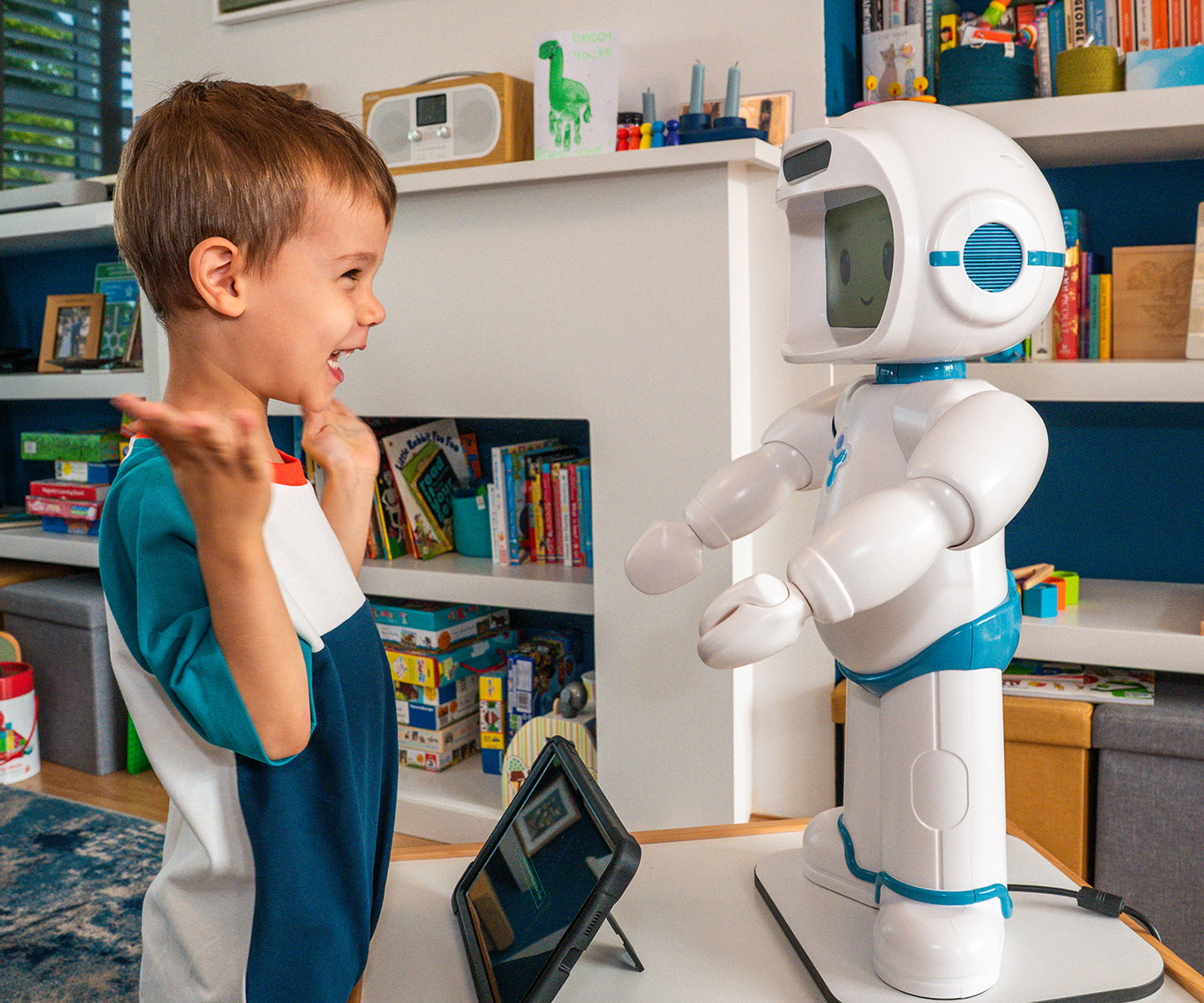 Young boy laughs while interacting with a child-friendly robot