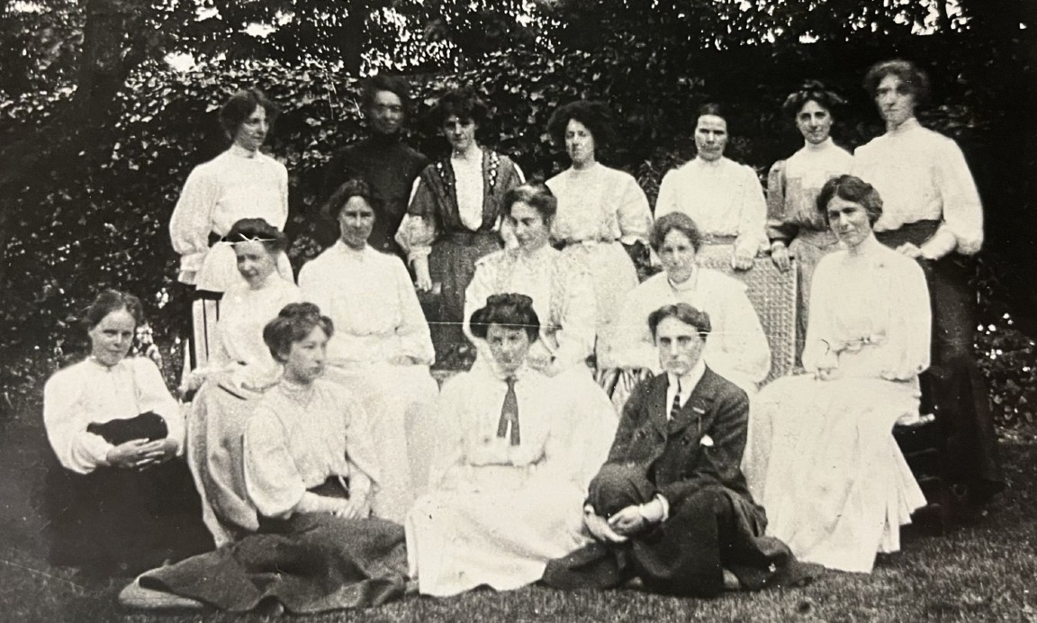 A group of women wearing 1920s clothes posing for a formal photo in a garden