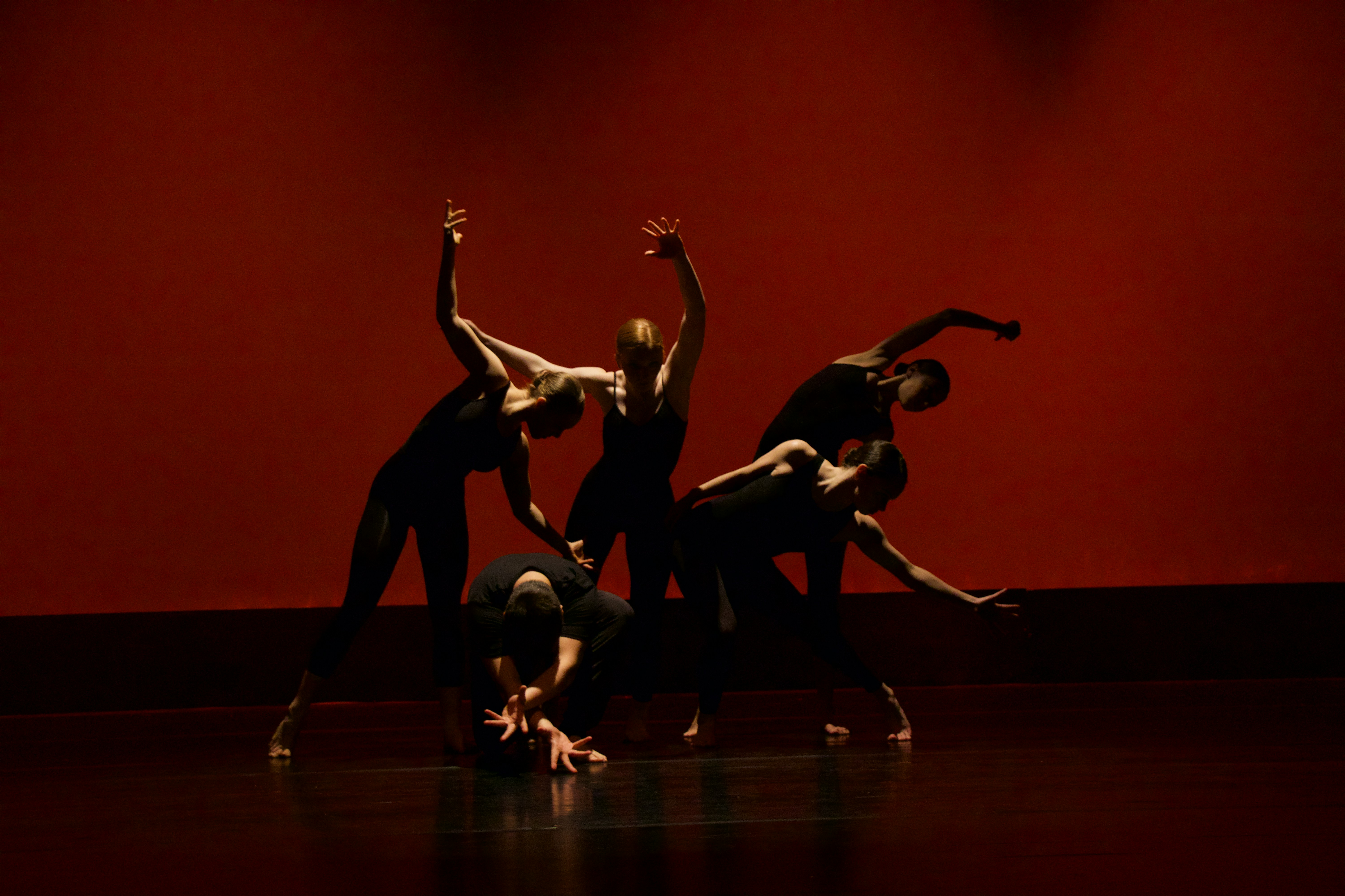 Group of ballet dancers in front of red screen