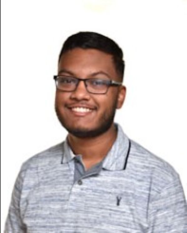 student ambassador sanjay wearing a grey t-shirt smiling with glasses on