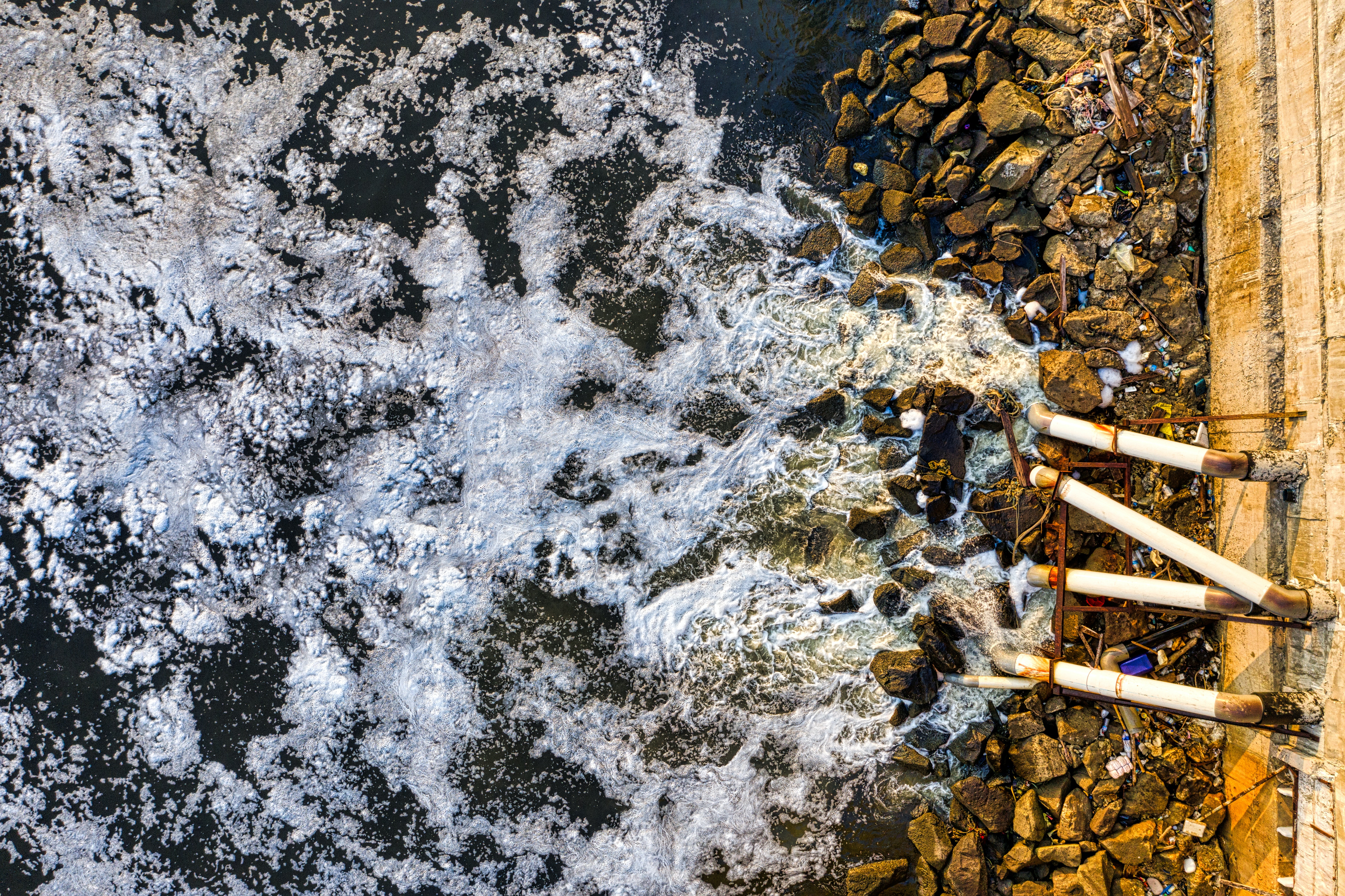 Water Waves Hitting Rocks while sewage is piped into the sea in Jakarta Indonesia