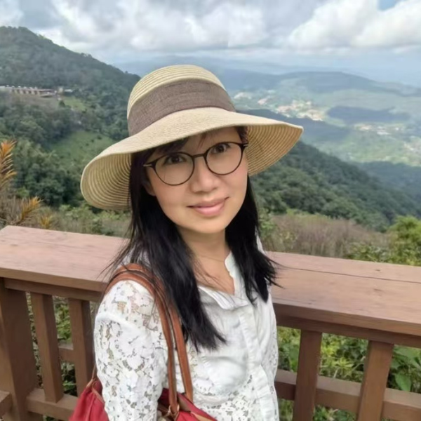 Sherry Chen, University of Birmingham alumna, standing in front of a forest and mountains