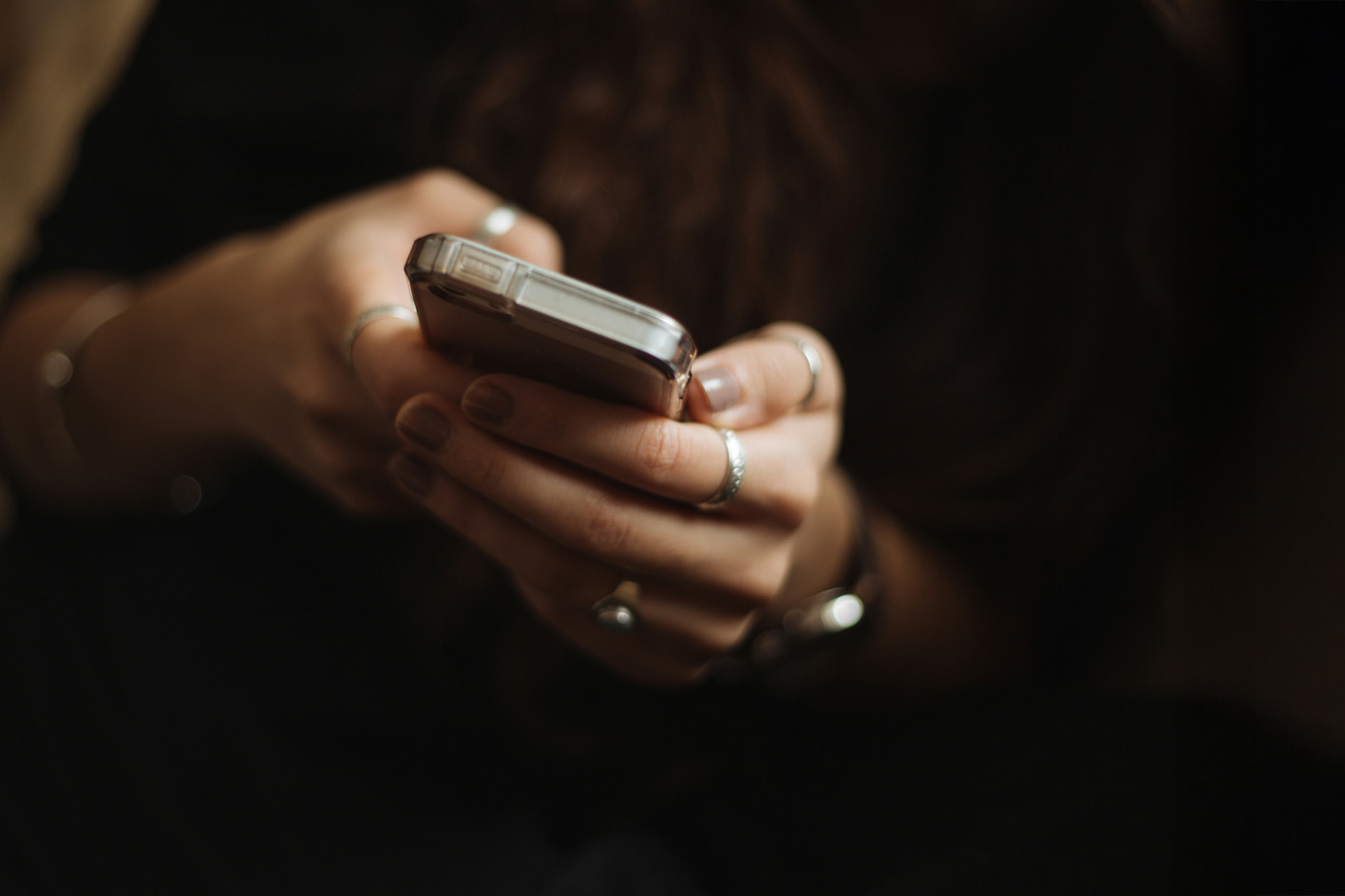 A pair of hands holding a smartphone in low light