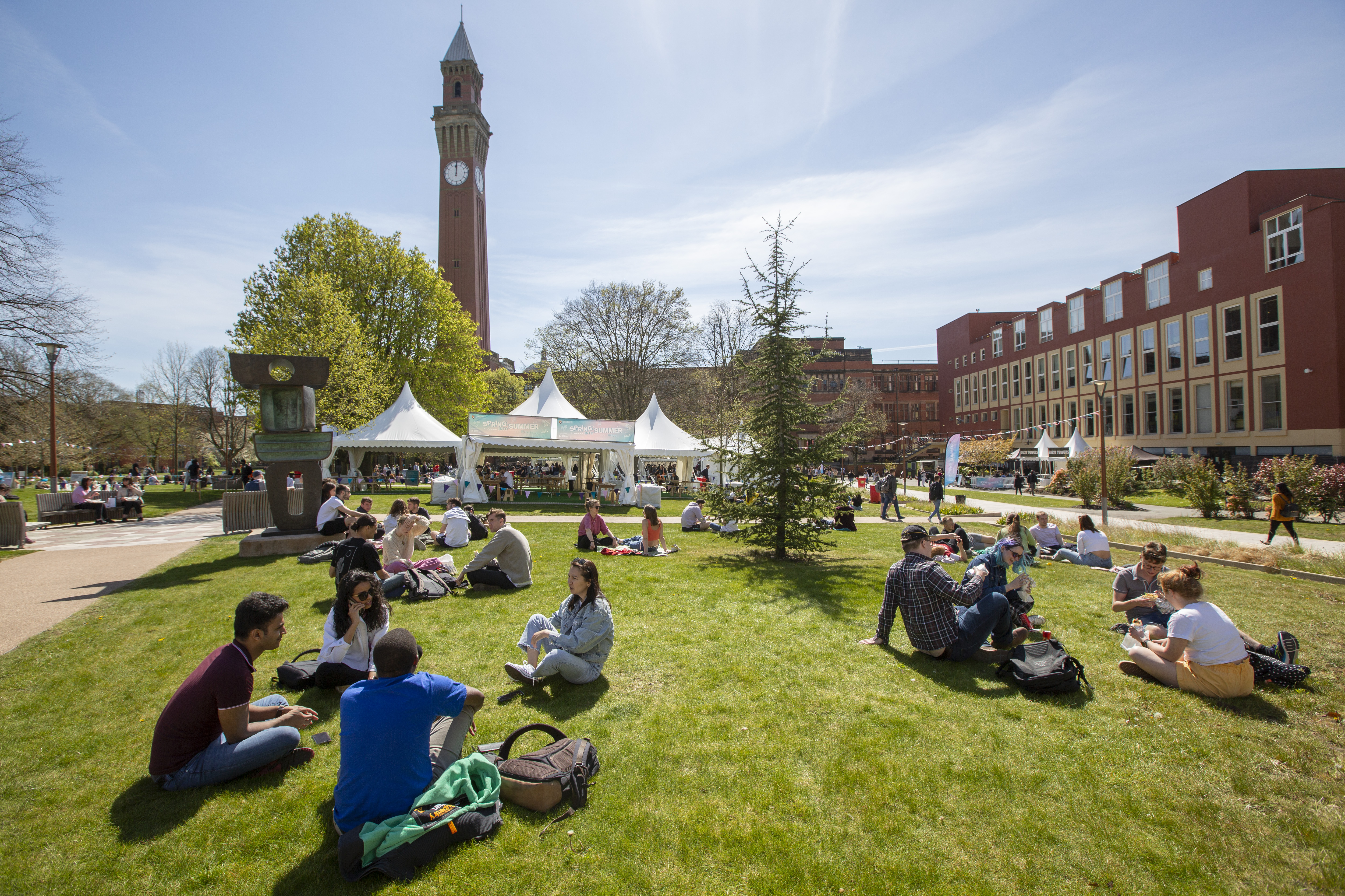 Students sitting on the grass in front of Old Joe clock tower.