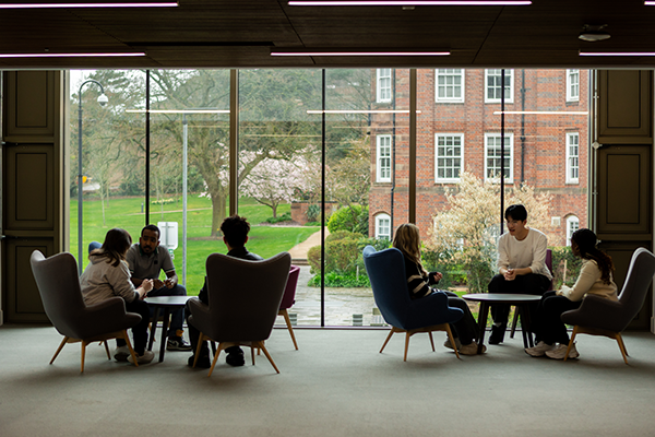 Two groups of students sitting around tables in the Birmingham Business School