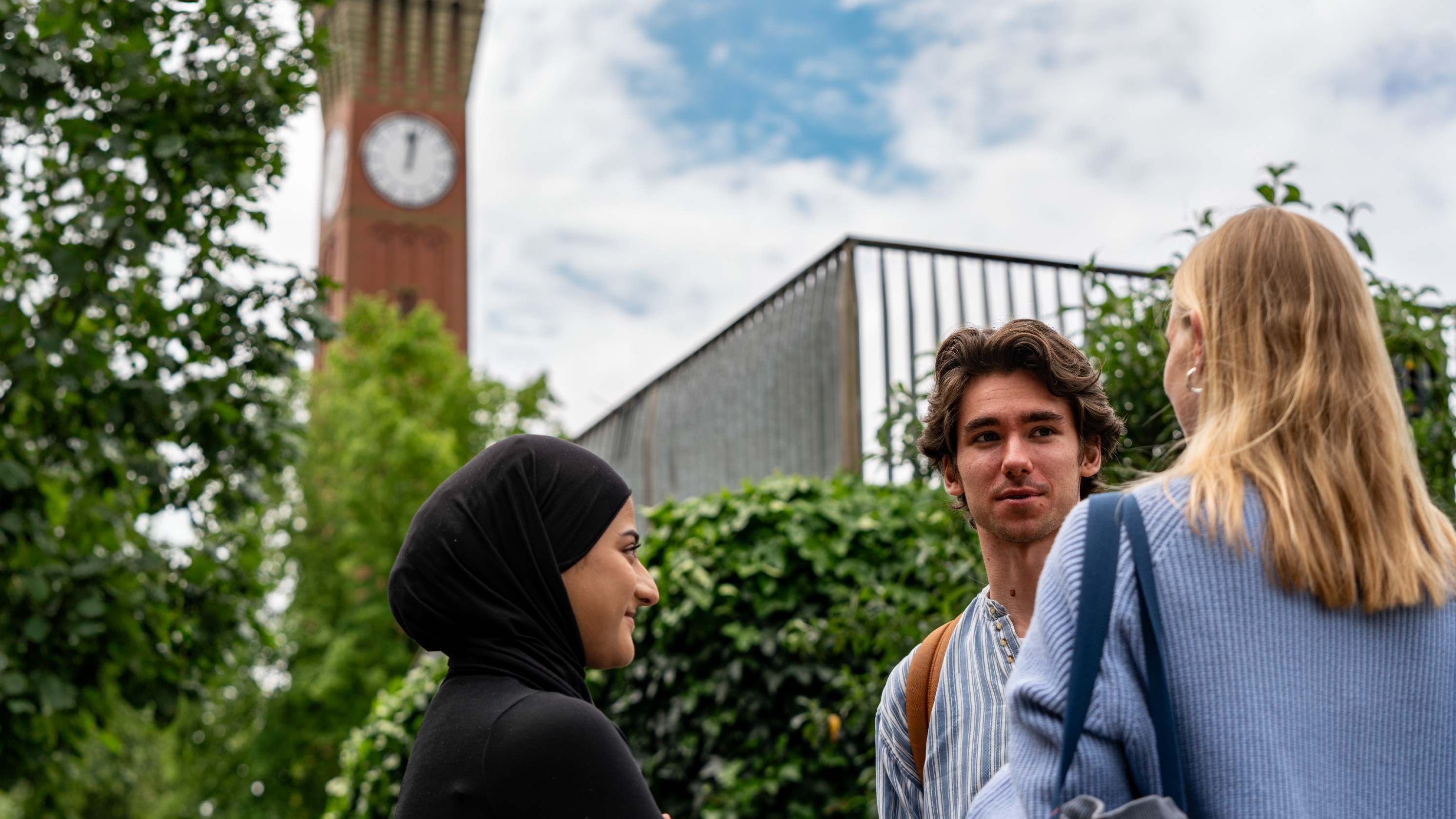 3 students talking with Old Joe in the background