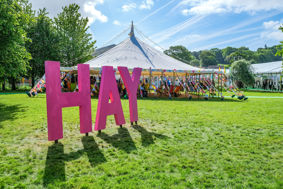 Pink sign saying 'Hay' outside a tent at Hay Festival.