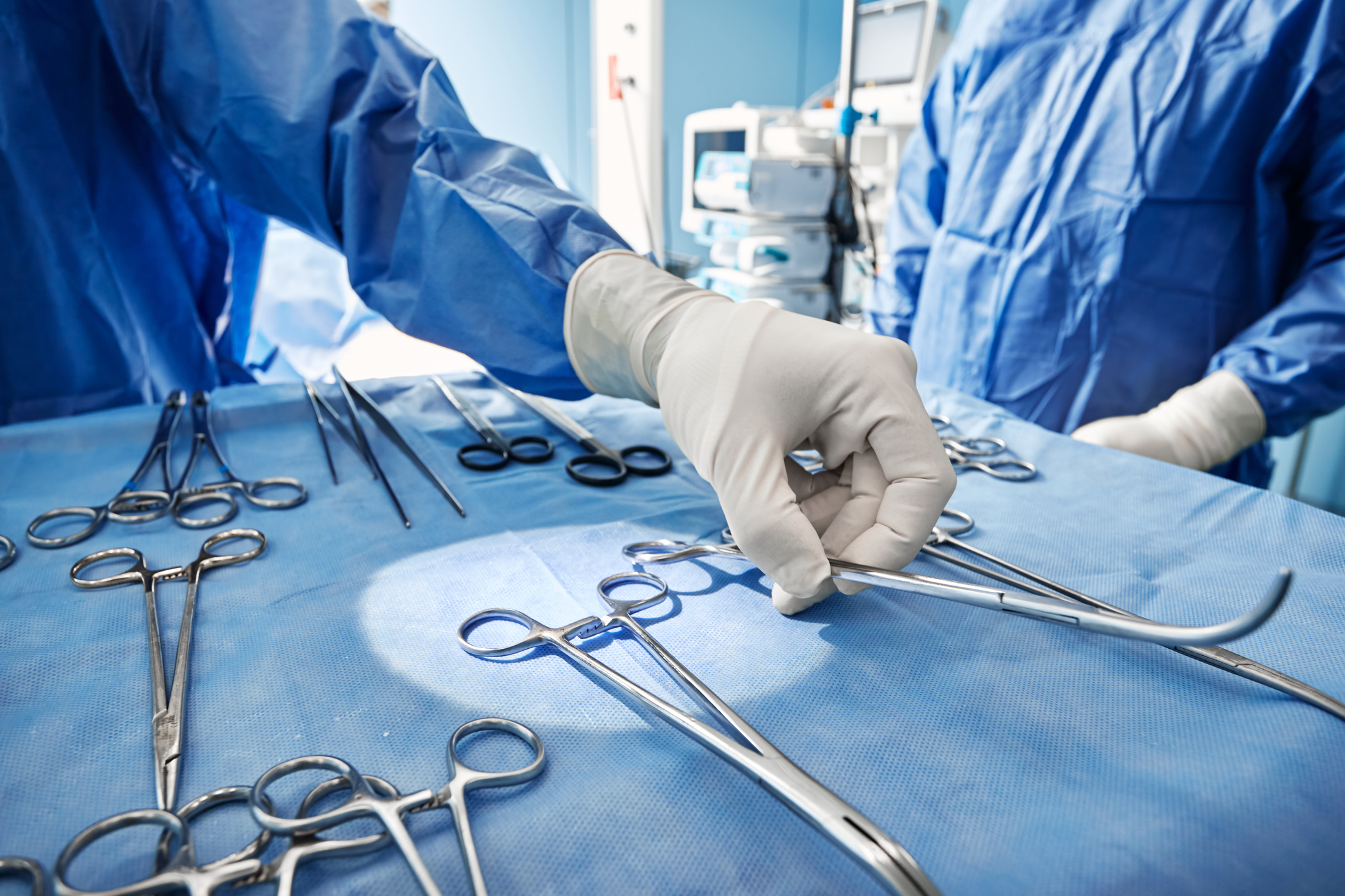 Surgeon in scrubs reaching for a tool 