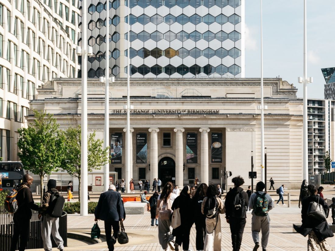 A large historic building with stone pillars and a sign reading, 'The Exchange, University of Birmingham' 