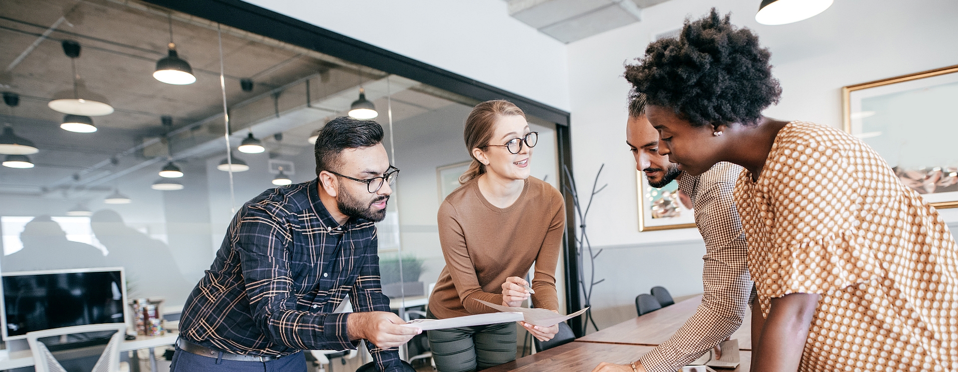 A team lean across a table to discuss work