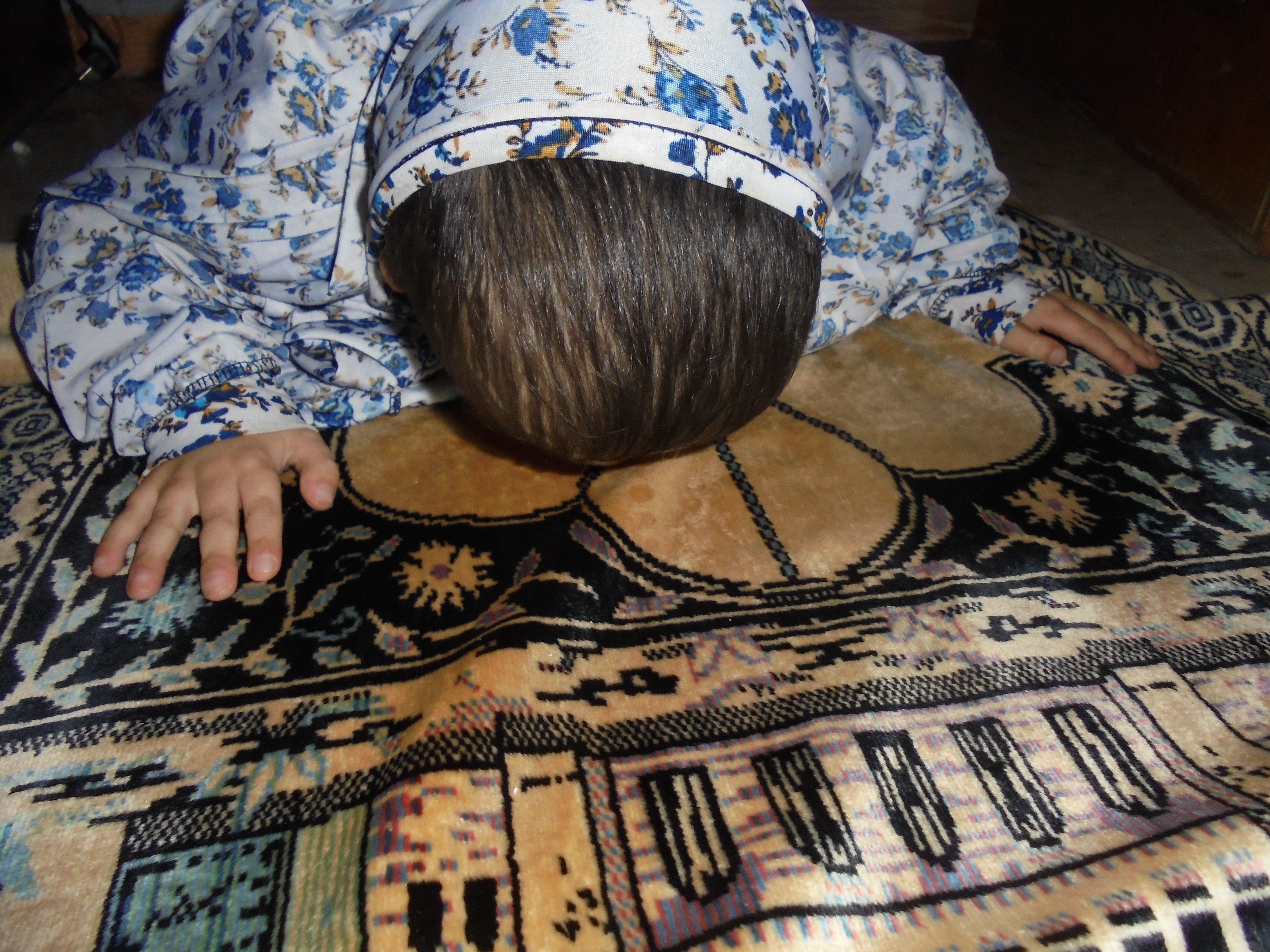 A young participant on the project, praying on the prayer mat, face down.