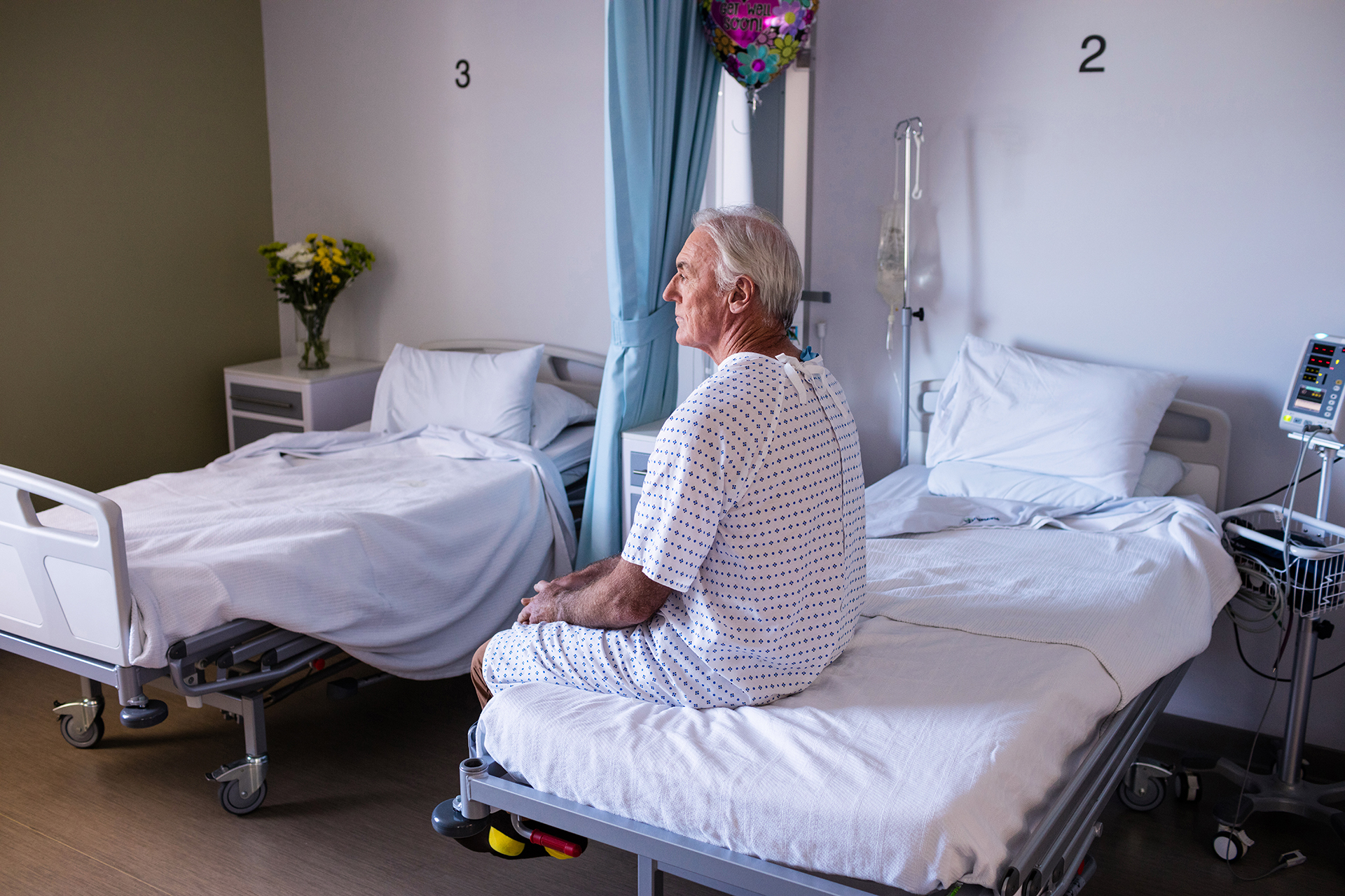 Male senior patient sitting in a hospital ward on a hospital bed