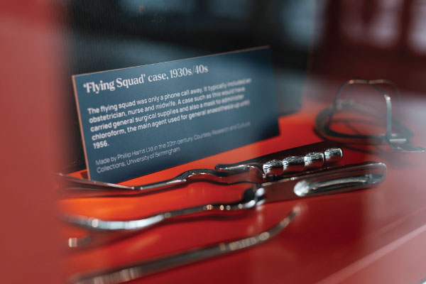 'A red display case with medical implements and a label titled " 'Flying Squad' case, 1930s/40s."