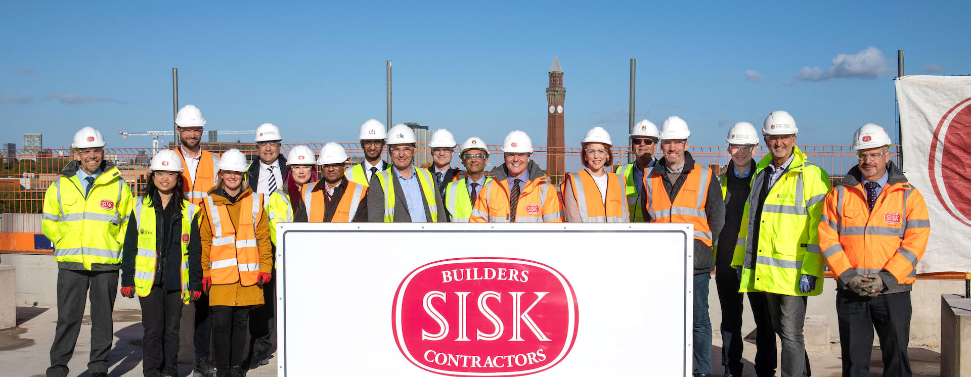 Group of people wearing high vis stand on top of No.1 BHIC building celebrating topping out ceremony
