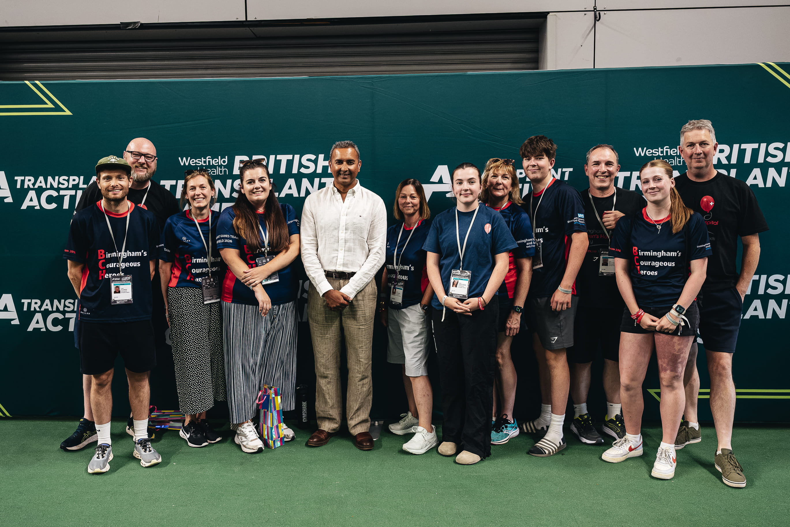 A smiling group of people wearing sports kit in front of a background that says British Transplant Games