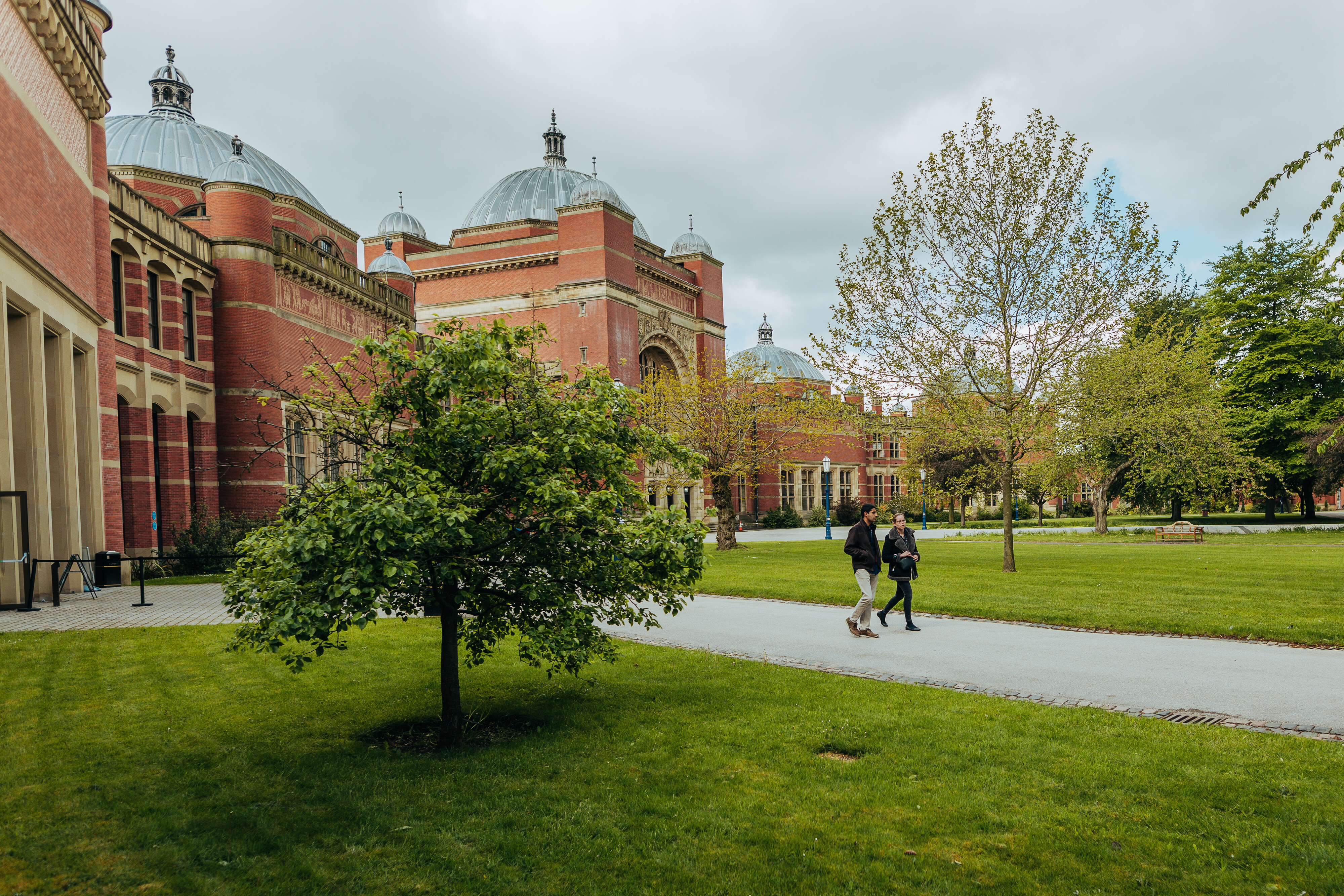 Two people walking on a pathway outside of the Aston Webb building