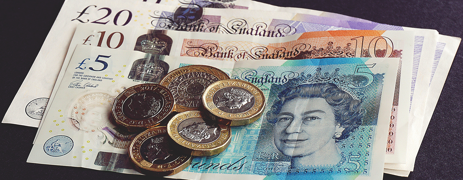 UK bank notes and coins on a black background