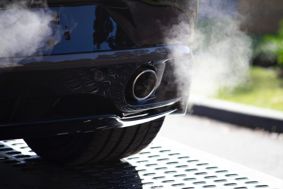 Exhaust pipe at the back of a black car with fumes