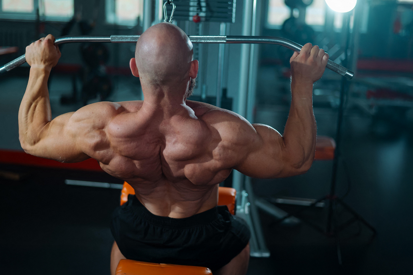 Muscly man using a lat pulldown machine in a gym setting