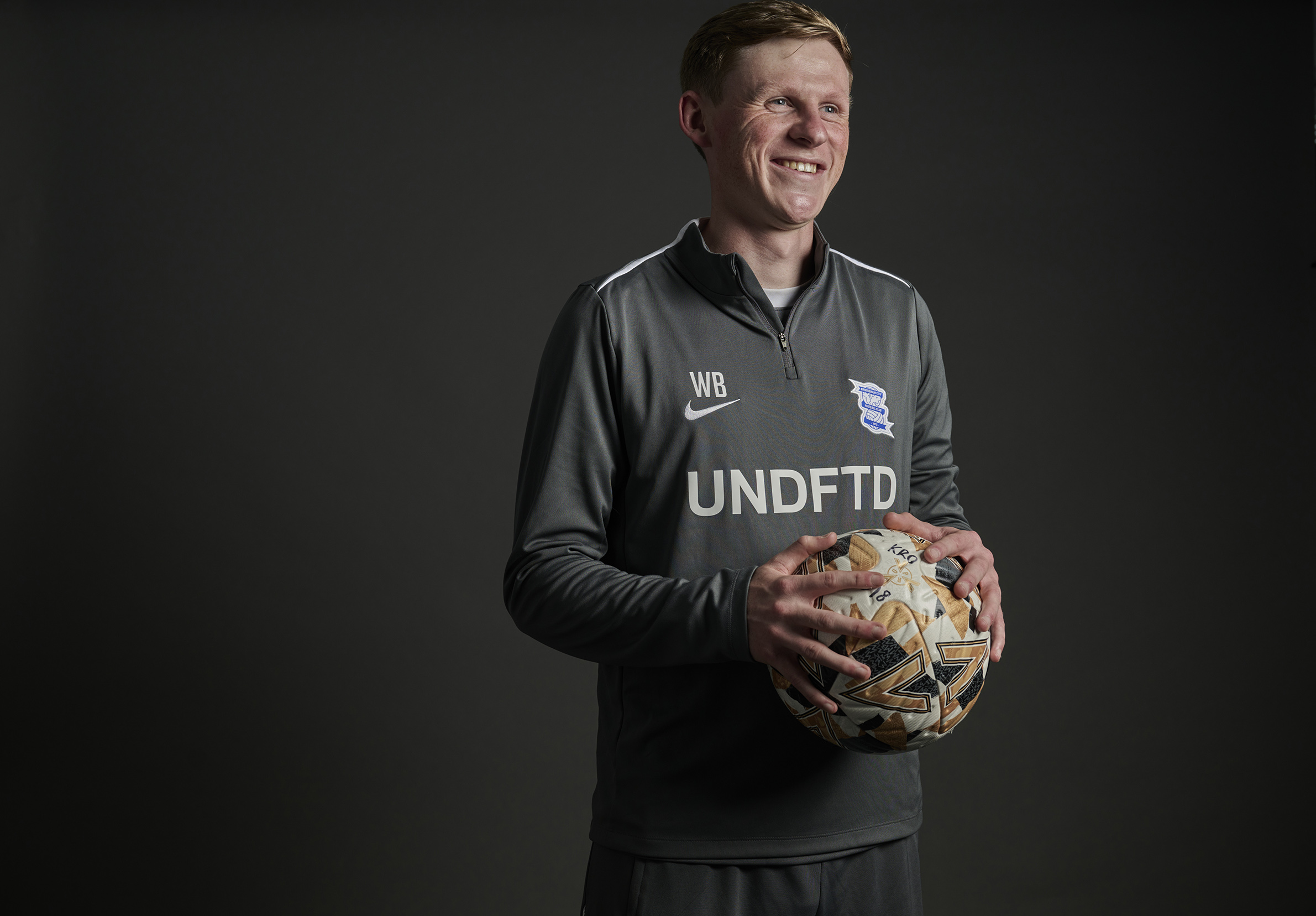 Male football physiotherapist holding a football